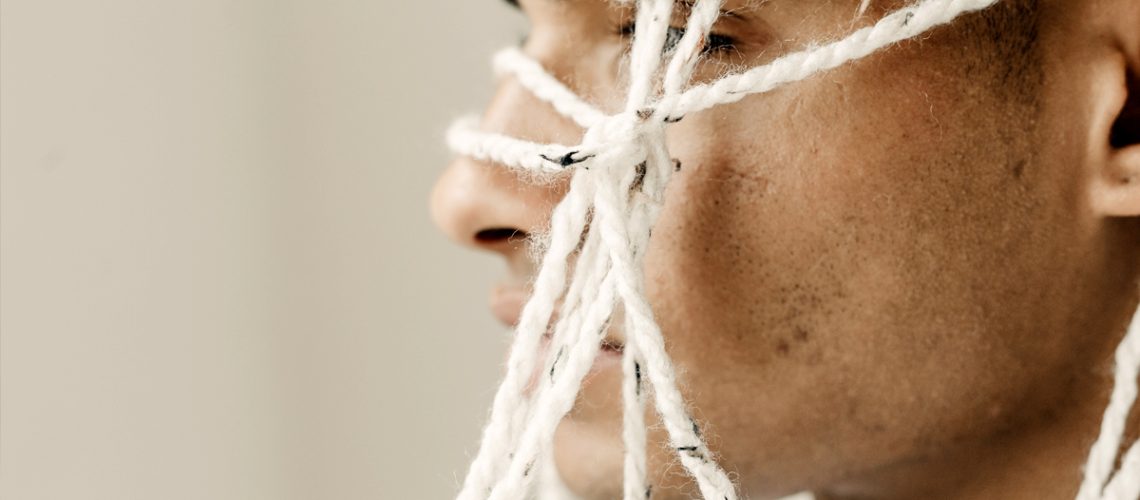 Sculptor working with string on his own face.